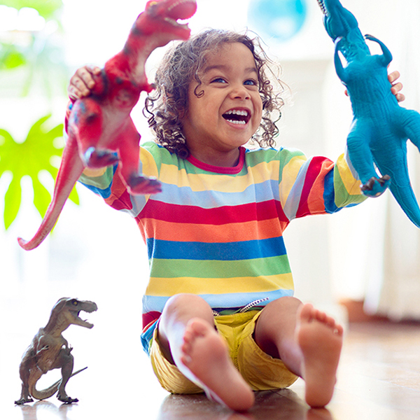 Child playing with colorful toy dinosaurs. Educational toys for kids. Little boy learning fossils and reptiles. Children play with dinosaur toys. Evolution and paleontology game for young kid.